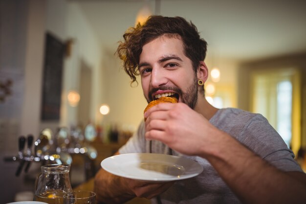 Man het eten van een croissant in cafÃ ©