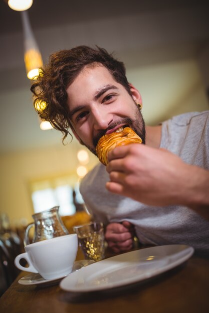 Man het eten van een croissant in cafÃ ©