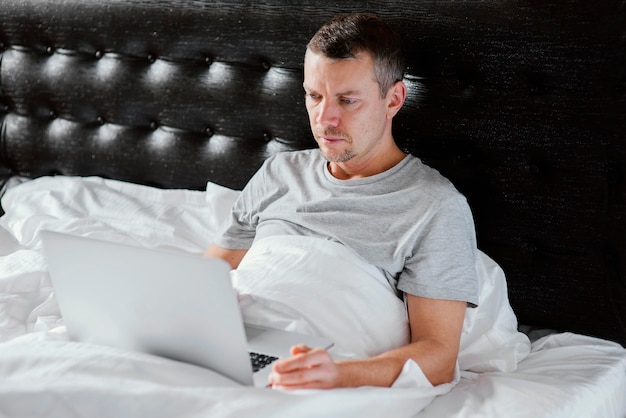 Gratis foto man in bed met laptop