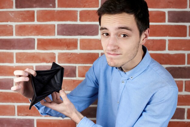 Man in blauw shirt met zwarte lege portemonnee