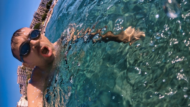 Man in bril zwemmen onder het blauwe en transparante water van de Middellandse Zee. De camera vasthouden