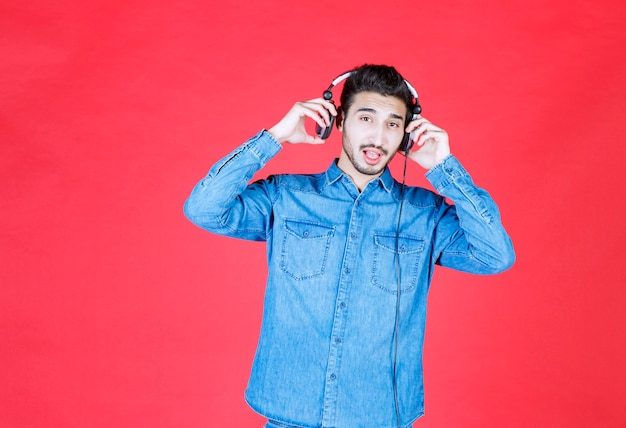 Man in denim shirt met koptelefoon en luisteren naar de nieuwe nummers.