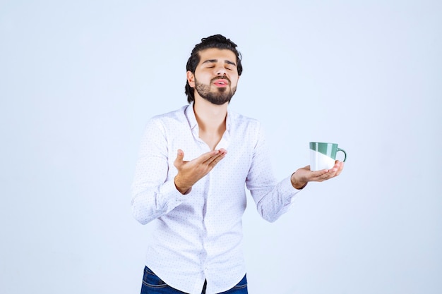 Man in een wit overhemd die een koffiemok vasthoudt en ervan geniet.