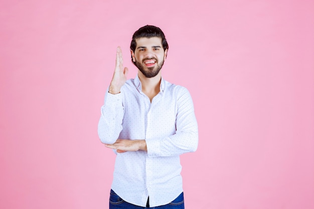 Man in een wit overhemd die zijn hand opsteekt om aandacht te krijgen of iets te laten zien.