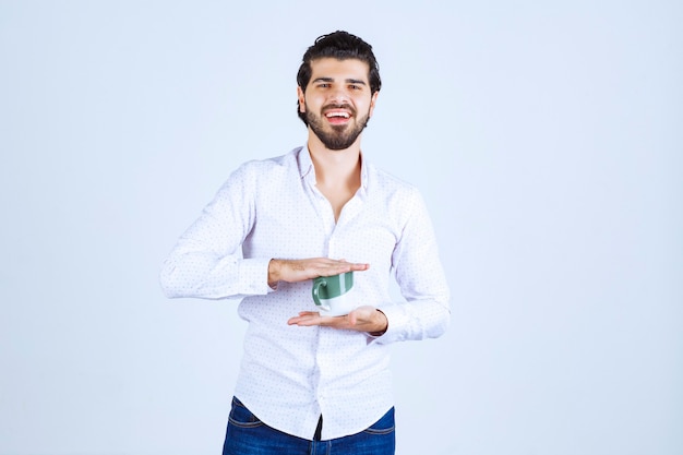 Man in een wit overhemd met een kopje koffie en ervan te genieten