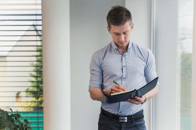 Man in formele kleding poseren met een notitieboekje