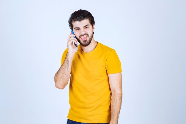 Man in geel shirt in gesprek met de telefoon.