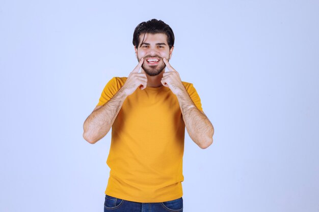 Man in geel shirt legt hand op zijn gezicht en lacht