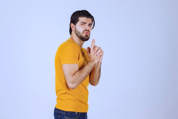 Man in geel shirt met pistoolteken in de hand