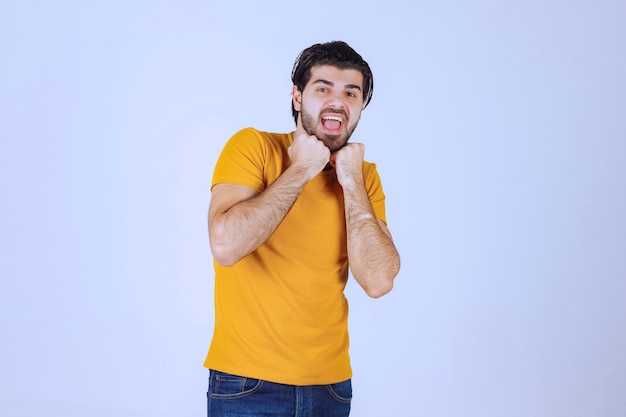 Man in geel shirt met zijn vuist en kracht