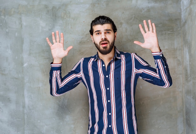 Man in gestreept shirt die hand opent en weigert.