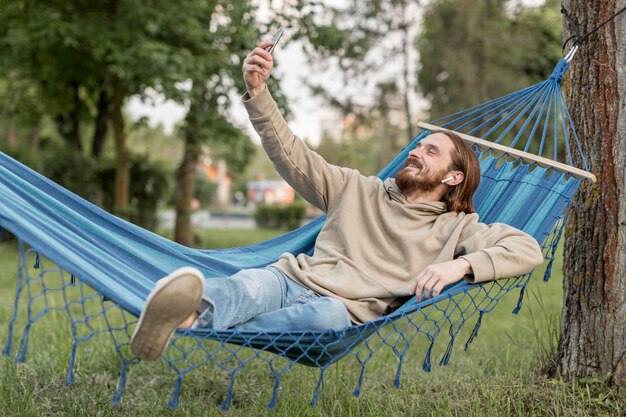 Man in hangmat nemen selfies met smartphone