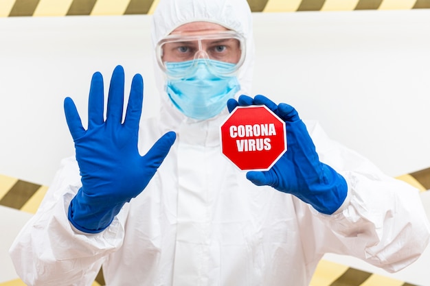 Gratis foto man in hazmat pak met coronavirus stopbord