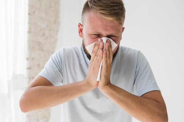 Man in het wit lijdt aan verkoudheid