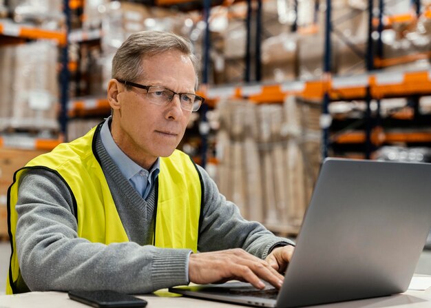 Gratis foto man in magazijn bezig met laptop