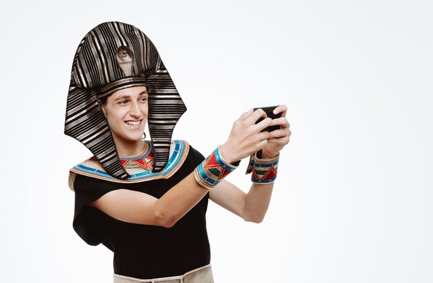 Man in oud Egyptisch kostuum die selfie maakt met smartphone gelukkig en positief op wit