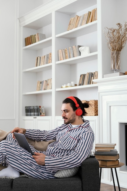 Man in pyjama met behulp van het zijaanzicht van de laptop