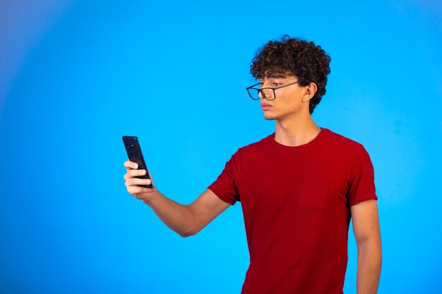 Man in rood shirt selfie te nemen of te bellen en kijkt verward.