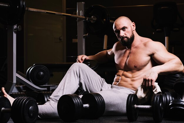 Man in sweatpants temidden van barbells