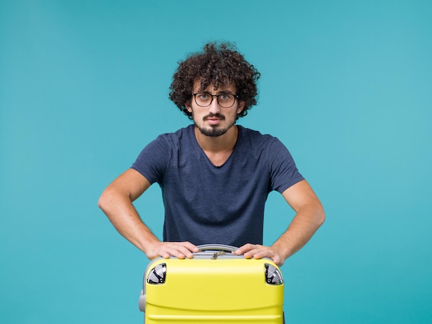 Man in vakantie met grote koffer op blauw