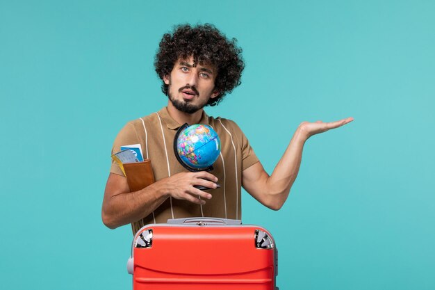 Man in vakantie met kleine wereldbol op blauw