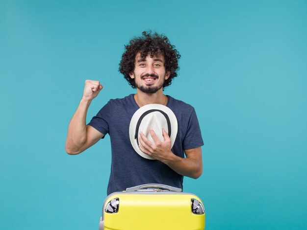 man in vakantie met zijn hoed op blauw