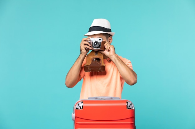 man in vakantie met zijn rode koffer die foto's maakt met camera op blauw