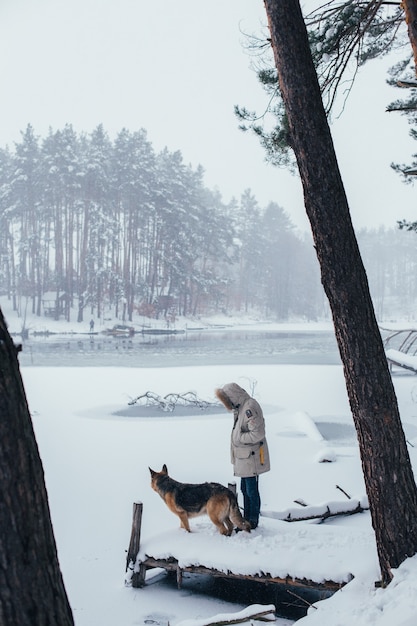 Man in winterjas in bos met herdershond