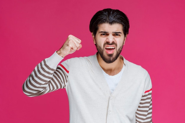 Man in wit overhemd met zijn vuist en biceps spieren.