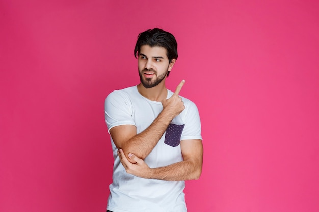 Man in wit overhemd wijst en presenteert iets aan de rechterkant.