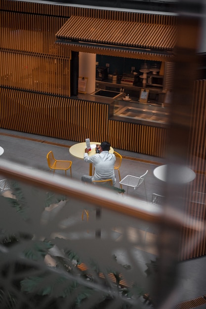 Man in wit shirt met lange mouwen zittend op een stoel in café