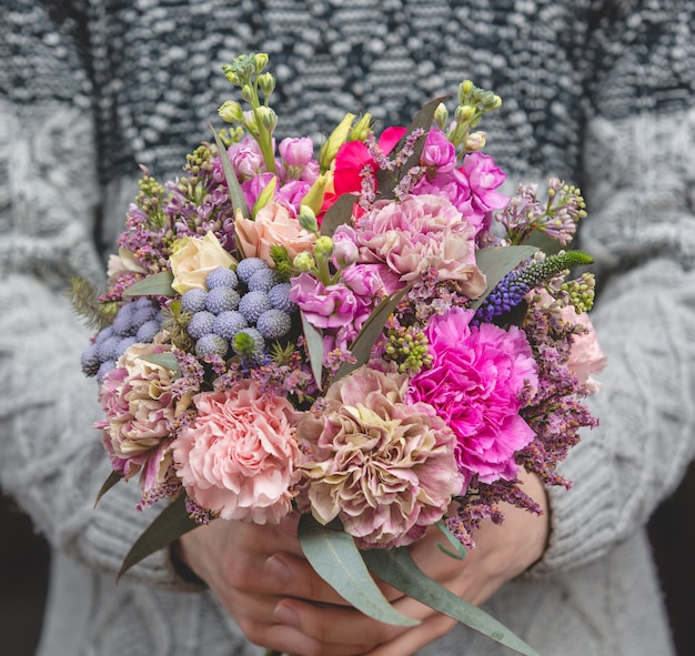 Man in wollen trui met een boeket van gemengde bloemen