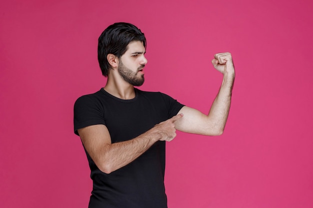 Man in zwart shirt met zijn vuist en armspieren.