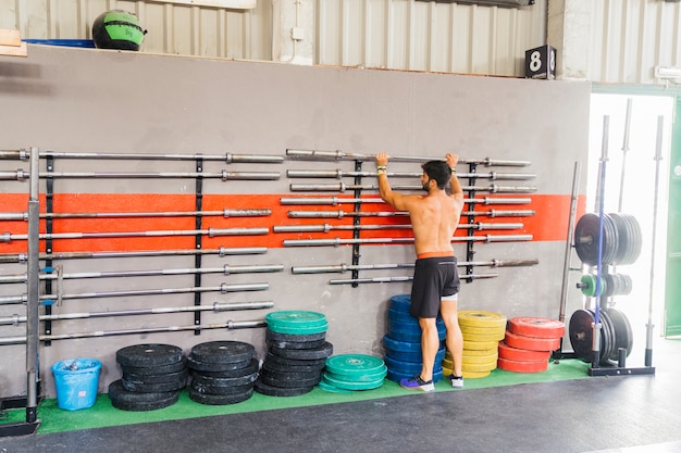 Gratis foto man kiezen barbell in de sportschool