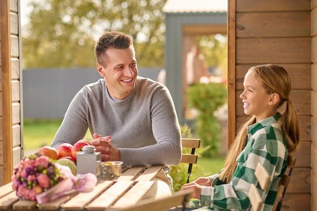 Man kijkt naar zijn lachende dochter die aan tafel zit