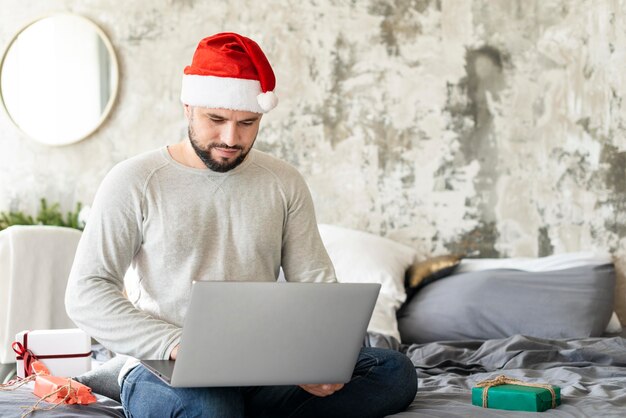 Man kijkt naar zijn laptop op eerste kerstdag met kopie ruimte