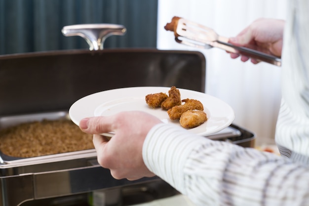 Gratis foto man kipnuggets op zijn bord in een cafetaria te zetten