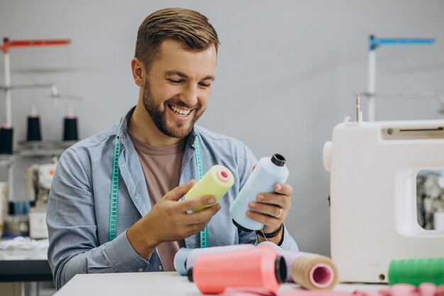 Man kleermaker aan het werk in zijn fabriek op naaimachine