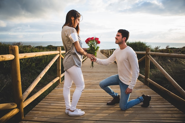 Man knielend overhandigen van een boeket rozen naar een vrouw