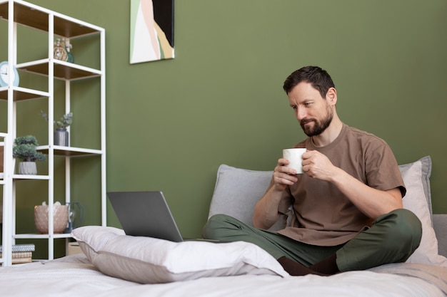 Gratis foto man koffie drinken op bed