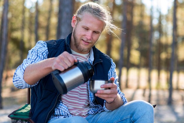 Man koffie uit thermos gieten