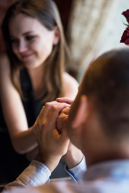 Man kussende hand van glimlachende vrouw