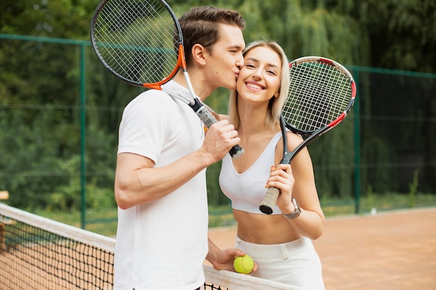 Man kussende vrouw op de tennisbaan