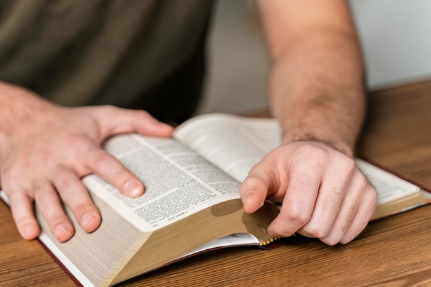 Man leest uit de bijbel op tafel