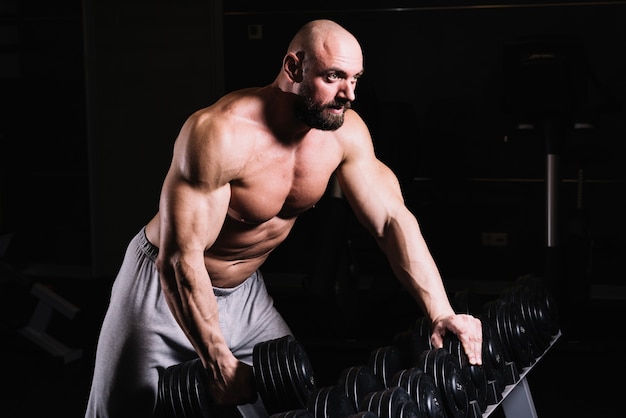 Man lifting weights while leaning on rack