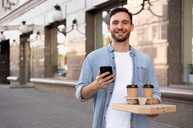 Man met afhaalmaaltijden op straat met smartphone