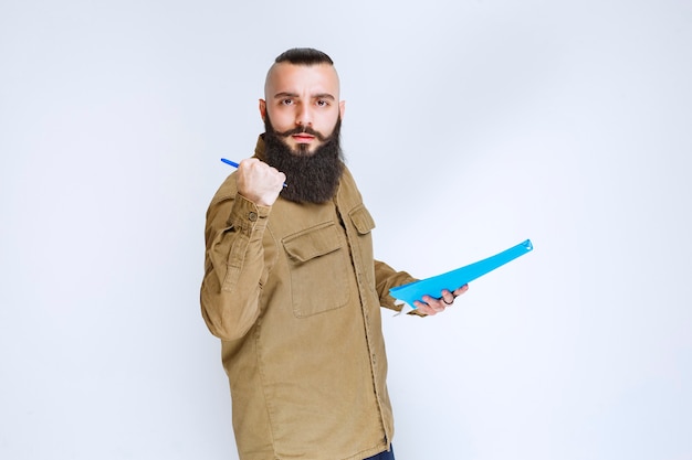 Man met baard die de rapportmap vasthoudt en naar zijn collega wijst.