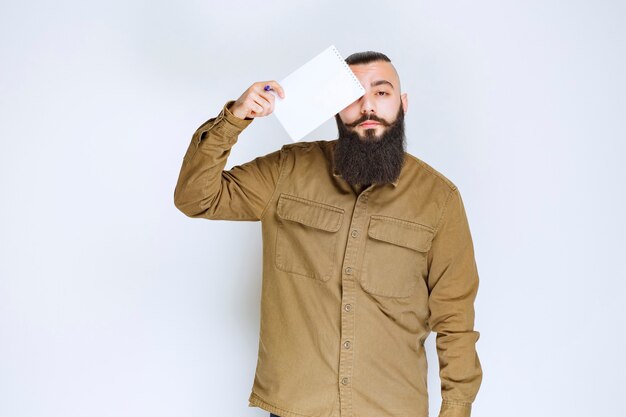 Man met baard die een quizpapier vasthoudt en er verward en attent uitziet.