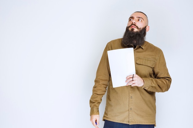 Man met baard die een quizpapier vasthoudt en er verward en attent uitziet.