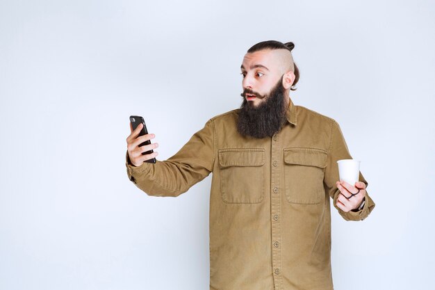 Man met baard die zijn berichten met verrassing controleert.